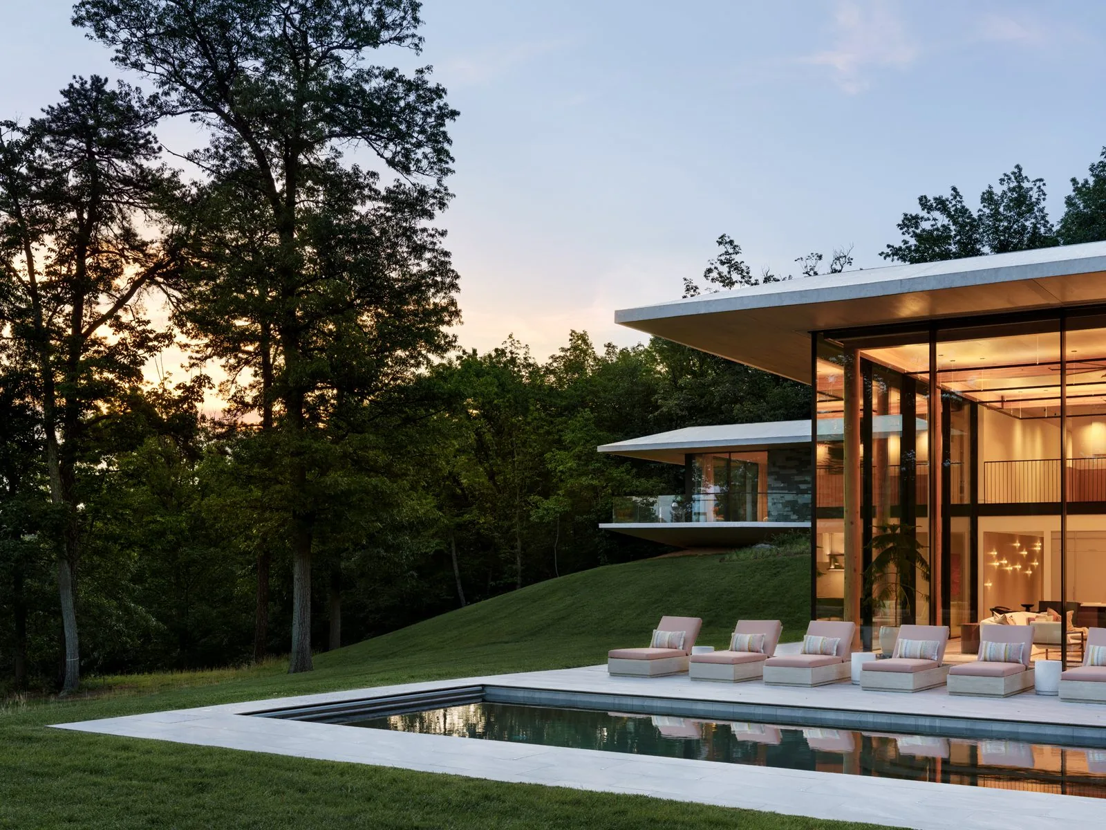 Modern Gruver Cooley home with glass walls and a pool at dusk